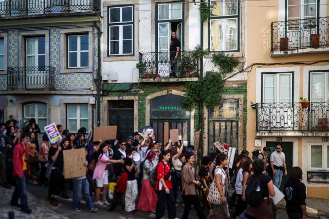 A man watches from his balcony as students demonstrate to ask affordable housing, an end to tuition fees, and investment in social programs in Lisbon on March 24, 2026. University students across the country  demonstrate on “Student Day" to demand affordable housing, an end to tuition fees, and investment in social programs. (Photo by PATRICIA DE MELO MOREIRA / AFP)