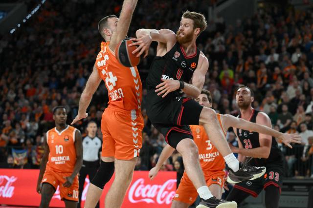 Olympiacos Piraeus' US guard #00 Thomas Walkup is defended by Valencia's Ivorian center #24 Mathew Costello during the Euroleague basketball match between Valencia Basket and Olympiacos at the Roig arena in Valencia on March 24, 2026. (Photo by JOSE JORDAN / AFP)