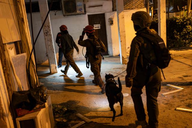 Security forces and first responders walk next to a damaged building at a site struck by a projectile in Bnei Brak, on the eastern outskirts of Tel Aviv, on March 24, 2026. The Middle East was sparked by joint US-Israeli strikes on Iran that triggered a wave of retaliatory missile and drone attacks against Israel and several other countries in the region. (Photo by Ilia YEFIMOVICH / AFP) / 