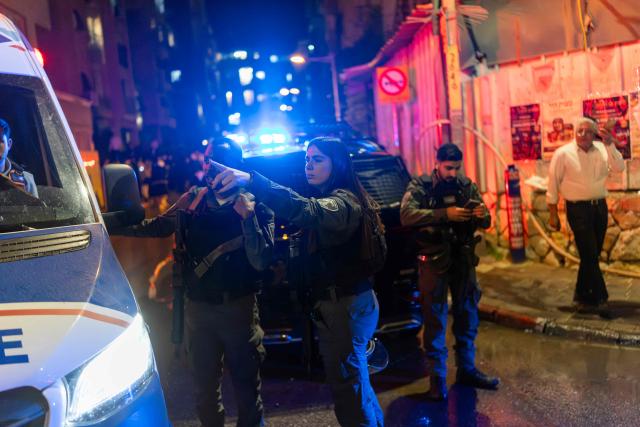 Police look towards a damaged building at a site struck by a projectile in Bnei Brak, on the eastern outskirts of Tel Aviv, on March 24, 2026. The Middle East was sparked by joint US-Israeli strikes on Iran that triggered a wave of retaliatory missile and drone attacks against Israel and several other countries in the region. (Photo by Ilia YEFIMOVICH / AFP) / 