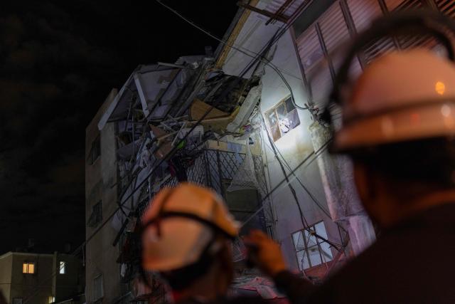 Security forces and first responders shine a torch into a damaged building at a site struck by a projectile in Bnei Brak, on the eastern outskirts of Tel Aviv, on March 24, 2026. The Middle East was sparked by joint US-Israeli strikes on Iran that triggered a wave of retaliatory missile and drone attacks against Israel and several other countries in the region. (Photo by Ilia YEFIMOVICH / AFP) / 