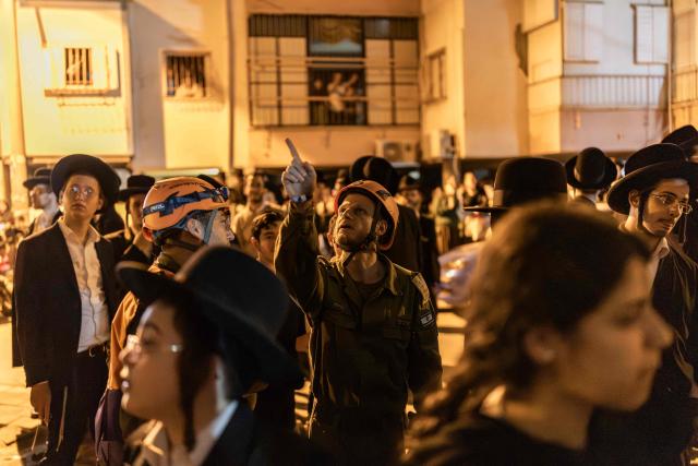 Security forces and first responders gather next to a damaged building at a site struck by a projectile in Bnei Brak, on the eastern outskirts of Tel Aviv, on March 24, 2026. The Middle East was sparked by joint US-Israeli strikes on Iran that triggered a wave of retaliatory missile and drone attacks against Israel and several other countries in the region. (Photo by Ilia YEFIMOVICH / AFP) / 