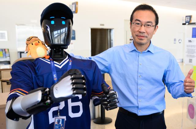 Lei Yang, CEO of InBot, poses with AI-powered robot named Jose that greets travelers, answers questions and provides real-time information is displayed during a media event at San Jose Mineta International Airport in San Jose, California, on March 24, 2026. Developed by local AI startup IntBot, the robot is part of a four-month engagement with SJC and will be stationed in Terminal B, Gate 24. Jose is designed to greet travellers and answer questions while providing real-time information in over 50 languages. (Photo by JOSH EDELSON / AFP)