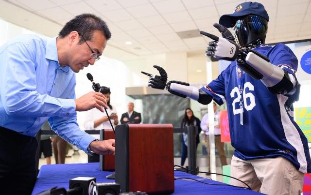 Lei Yang, CEO of InBot, asks questions to AI-powered robot named Jose that greets travelers, and provides real-time information is displayed during a media event at San Jose Mineta International Airport in San Jose, California, on March 24, 2026. Developed by local AI startup IntBot, the robot is part of a four-month engagement with SJC and will be stationed in Terminal B, Gate 24. Jose is designed to greet travellers and answer questions while providing real-time information in over 50 languages. (Photo by JOSH EDELSON / AFP)