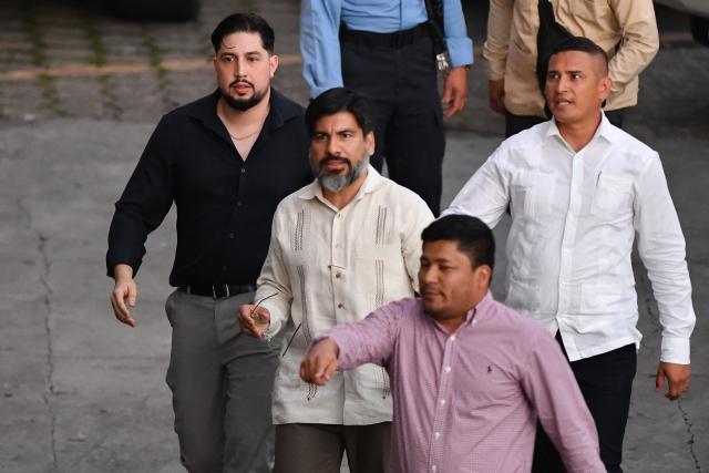 The suspended Attorney General of the Republic, Joel Zelaya (C), leaves Honduras’ Congress after appearing at a congressional committee hearing that launched an impeachment process against him in Tegucigalpa on March 24, 2026. Honduras’ Congress, controlled by the right, suspended Attorney General Johel Zelaya on the night of March 23, 2026. Zelaya, who is close to the previous leftist government, was removed to face an impeachment trial on accusations of abuse of authority and persecution during last November’s elections. (Photo by Orlando SIERRA / AFP)