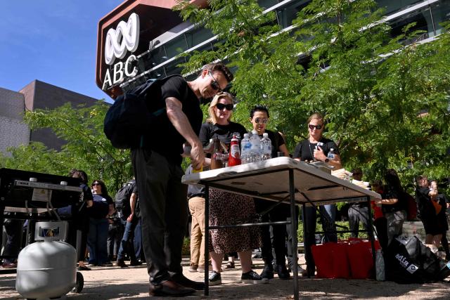 Journalists and staff line up for a sausage sizzle outside the Australian Broadcasting Corporation (ABC) headquarters during a strike demanding better pay and protections to stop artificial intelligence taking their jobs, in Melbourne on March 25, 2026. The ABC was forced to replace live programming with pre-recorded shows after more than 2,000 journalists and staff called a 24-hour strike. (Photo by William WEST / AFP)