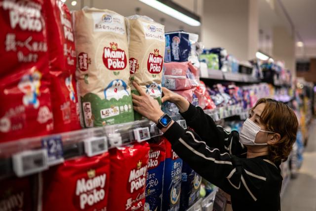 This picture taken on January 15, 2026 shows a staff member in a supermarket managing diaper products in Aira city, Kagoshima Prefecture. A pilot project, billed as a world first, reuses the main ingredient in nappies to make new ones, offering hopes to ease bloated landfill sites and respond to a growing need for adult diapers in ageing Japan. (Photo by Philip FONG / AFP) / TO GO WITH: Japan-environment-manufacturing-diapers-demographics, FOCUS