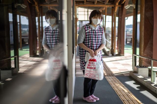 This picture taken on January 16, 2026 shows a staff collecting a bag of used diapers at a nursery school in Osaki town, Kagoshima Prefecture. A pilot project, billed as a world first, reuses the main ingredient in nappies to make new ones, offering hopes to ease bloated landfill sites and respond to a growing need for adult diapers in ageing Japan. (Photo by Philip FONG / AFP) / TO GO WITH: Japan-environment-manufacturing-diapers-demographics, FOCUS