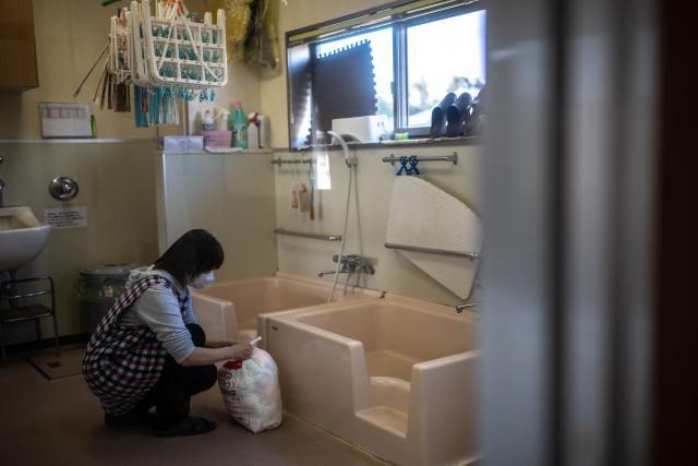 This picture taken on January 16, 2026 shows a staff collecting a bag of used diapers at a nursery school in Osaki town, Kagoshima Prefecture. A pilot project, billed as a world first, reuses the main ingredient in nappies to make new ones, offering hopes to ease bloated landfill sites and respond to a growing need for adult diapers in ageing Japan. (Photo by Philip FONG / AFP) / TO GO WITH: Japan-environment-manufacturing-diapers-demographics, FOCUS
