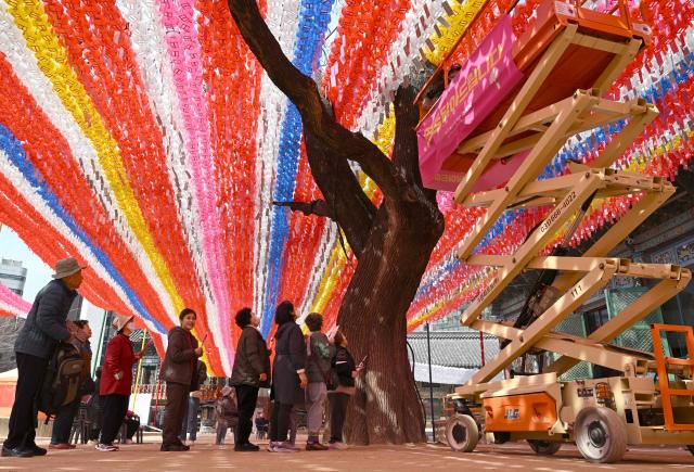 Buddhist followers wait in line to attach their wish cards to lotus lanterns installed for upcoming celebrations of Buddha's birthday at Jogyesa Temple in Seoul on March 25, 2026. (Photo by Jung Yeon-je / AFP)