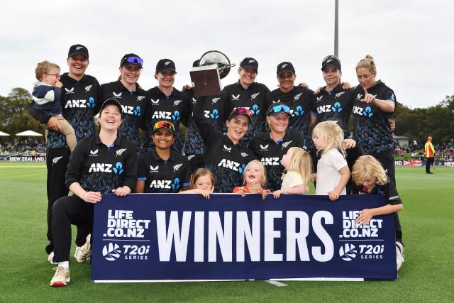 New Zealand's Amelia Kerr (C) holds the series trophy and poses with teammates after winning the fifth Twenty20 international women's cricket match between New Zealand and South Africa at Hagley Oval in Christchurch on March 25, 2026. (Photo by Sanka Vidanagama / AFP)