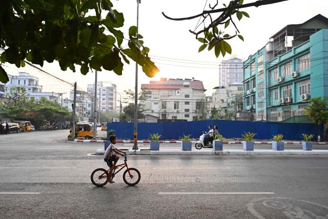 This photo taken on March 19, 2026 shows people commuting past the site of a cleared building in Mandalay after a magnitude 7.7 magnitude earthquake on March 28, 2025. The magnitude 7.7 magnitude earthquake on March 28, 2025 killed more than 3,700 people as it razed buildings in Myanmar's central belt, with devastation focused on the second-most-populous city of Mandalay. (Photo by Sai Aung MAIN / AFP)