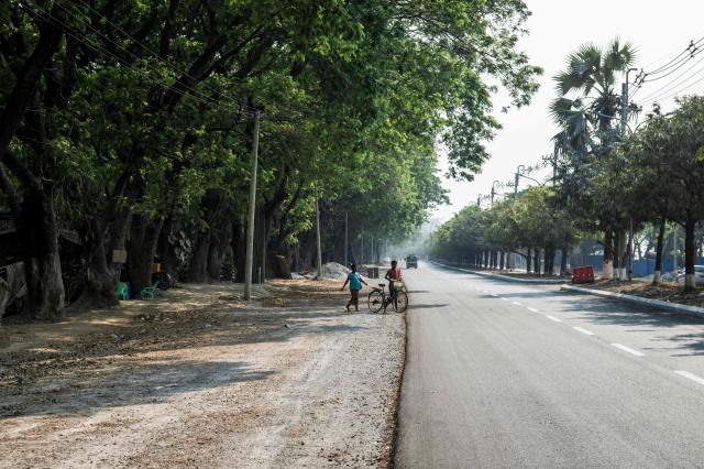 This photo taken on March 19, 2026 shows people crossing a repaired road in Mandalay after a magnitude 7.7 magnitude earthquake on March 28, 2025. The magnitude 7.7 magnitude earthquake on March 28, 2025 killed more than 3,700 people as it razed buildings in Myanmar's central belt, with devastation focused on the second-most-populous city of Mandalay. (Photo by Sai Aung MAIN / AFP)