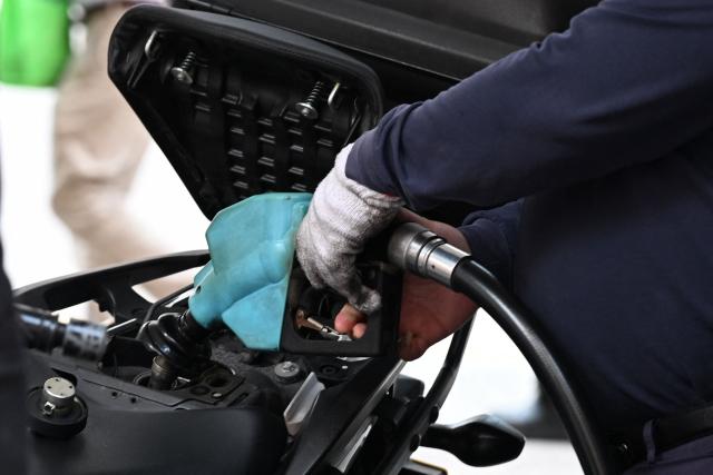 A pump attendant fills up a motorcycle at a petrol station in Hong Kong on March 25, 2026. (Photo by Peter PARKS / AFP)