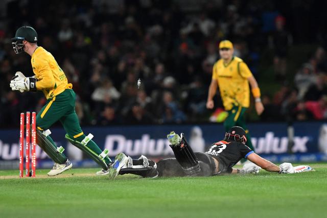 New Zealand's Tim Robinson (R) dives to reach the crease as South Africa's wicketkeeper Rubin Hermann successfully runs him out during the fifth Twenty20 international cricket match between New Zealand and South Africa at Hagley Oval in Christchurch on March 25, 2026. (Photo by Sanka Vidanagama / AFP)