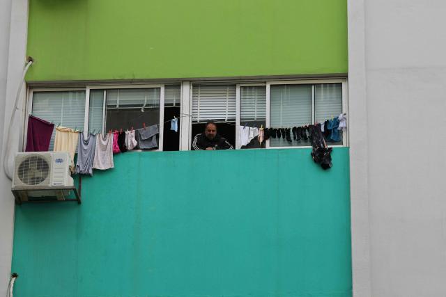 A displaced Lebanese man stands next to hanging laundry hanging from the window of a classroom of a public school that has been converted into a shelter in the town of Dekwaneh, north of Beirut on March 25, 2026. Lebanon was pulled into the Middle East war when the Tehran-backed Hezbollah militant group began firing rockets into Israel on March 2 to avenge the killing of Iran's supreme leader on February 28 by the US and Israel. Israel has since launched strikes across Lebanon, killing at least 1,039 people and displacing more than a million others in more than three weeks of fighting. It has also sent ground troops into the country's south. (Photo by Anwar AMRO / AFP)