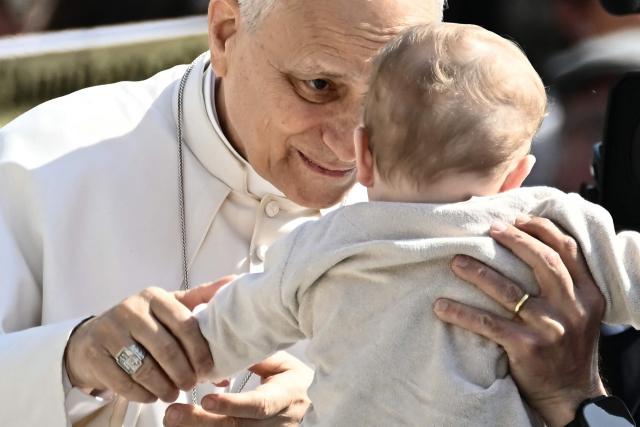Pope Leo XIV blesses a baby during the weekly general audience at St Peter's Square in The Vatican on March 25, 2026. (Photo by Filippo MONTEFORTE / AFP)