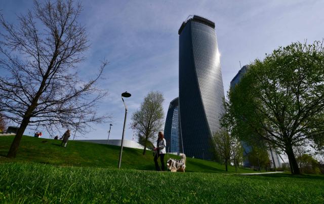 A woman walks her dog at the CityLife Shopping District in Milan, on March 25, 2026. (Photo by Stefano RELLANDINI / AFP)