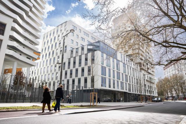 Pedestrians walk past the building intended to house the European Customs Authority in Lille, northern France, on March 25, 2026. Lille is competing to host the headquarters of the future European Customs Authority alongside Rome, Warsaw, Zagreb, Bucharest, The Hague, as well as Liege, Porto and Malaga. The choice of location will be made on March 25, 2026 in several stages, the European Council stated in a press release at the end of February. Firstly, the Council and the European Parliament will each select two of the candidate cities, without consulting one another. If the same city is selected by both institutions, it will automatically be chosen. In the event of a disagreement, the Council and the Parliament will proceed to a vote to reach a consensus. (Photo by Elise HOUBEN / AFP)