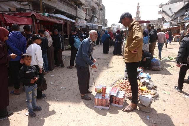 Displaced Palestinians shop for food at an open market in Khan Yunis, in the southern Gaza Strip on March 25, 2026. Since the terms of a US-brokered ceasefire deal came into effect on October 10, 2025, Israel remains in control of nearly half of the Gaza Strip, including all its border areas, imposing a strict blockade after the start of the war with Hamas in October 2023, prompting frequent calls for more aid trucks to be allowed into the territory from UN agencies and international NGOs. Since the strat of the war the majority of Gaza's 2.4 million people have been displaced, often multiple times. (Photo by Bashar Taleb / AFP)