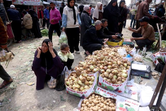 Displaced Palestinians shop for food at an open market in Khan Yunis, in the southern Gaza Strip on March 25, 2026. Since the terms of a US-brokered ceasefire deal came into effect on October 10, 2025, Israel remains in control of nearly half of the Gaza Strip, including all its border areas, imposing a strict blockade after the start of the war with Hamas in October 2023, prompting frequent calls for more aid trucks to be allowed into the territory from UN agencies and international NGOs. Since the strat of the war the majority of Gaza's 2.4 million people have been displaced, often multiple times. (Photo by Bashar Taleb / AFP)