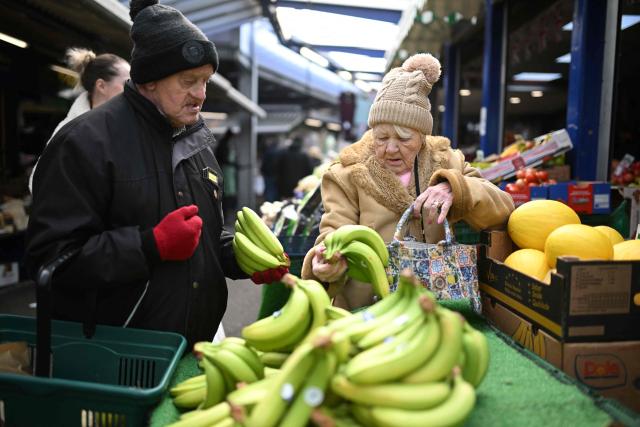 Shoppers look at bananas for sale at Bury Market in Bury, Greater Manchester on March 25, 2026. Britain's annual inflation rate was unchanged at 3.0 percent in February, official data showed on March 25 ahead of an expected jump as the Middle East war has sent oil prices surging. (Photo by Oli SCARFF / AFP)