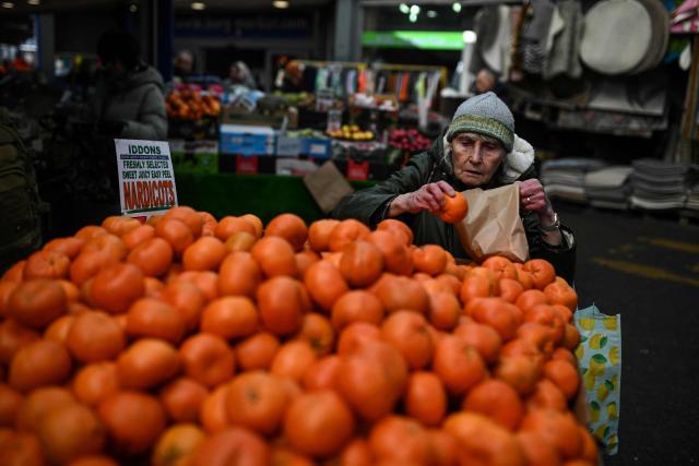 A shopper looks at fruit for sale at Bury Market in Bury, Greater Manchester on March 25, 2026. Britain's annual inflation rate was unchanged at 3.0 percent in February, official data showed on March 25 ahead of an expected jump as the Middle East war has sent oil prices surging. (Photo by Oli SCARFF / AFP)