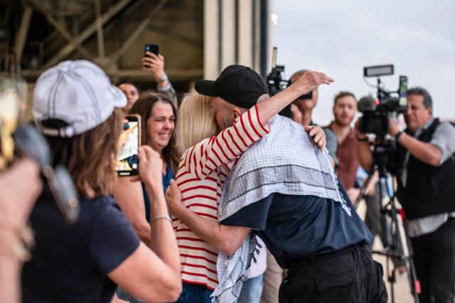 Dennis Coyle (in hat) embraces his mother as he arrives at Kelly Field at Joint Base San Antonio in San Antonio, Texas, on March 25, 2026. Afghanistan's Taliban government released Coyle, a US national, on March 24 after being detained for more than a year, after a letter from his family requesting his freedom. The foreign ministry said the family of linguist and researcher Dennis Coyle had written to the supreme leader of Afghanistan, asking that he be freed and pardoned for Eid. (Photo by SERGIO FLORES / AFP)