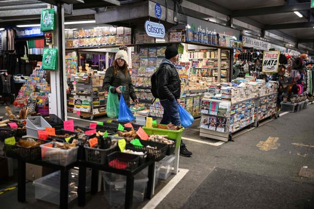 Shoppers make their way around various stalls at Bury Market in Bury, Greater Manchester on March 25, 2026. Britain's annual inflation rate was unchanged at 3.0 percent in February, official data showed on March 25 ahead of an expected jump as the Middle East war has sent oil prices surging. (Photo by Oli SCARFF / AFP)