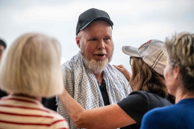 Dennis Coyle is greeted by family and friends as he arrives at Kelly Field at Joint Base San Antonio in San Antonio, Texas, on March 25, 2026. Afghanistan's Taliban government released Coyle, a US national, on March 24 after being detained for more than a year, after a letter from his family requesting his freedom. The foreign ministry said the family of linguist and researcher Dennis Coyle had written to the supreme leader of Afghanistan, asking that he be freed and pardoned for Eid. (Photo by SERGIO FLORES / AFP)