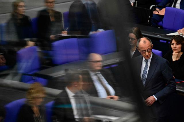 German Chancellor Friedrich Merz stands at a microphone as he answers questions from parliamentarians to the government during a question time at the Bundestag (lower house of parliament) in Berlin, on March 25, 2026. (Photo by John MACDOUGALL / AFP)
