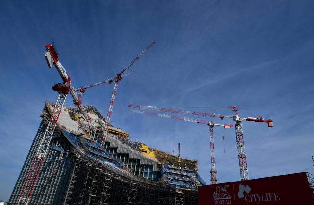 A picture shows cranes at the construction site of a new building called "CityWave", a reclining structure which extends horizontally with a large curved wave-shaped roof, covered with a huge photovoltaic park, at the CityLife district of Milan, on March 25, 2026. (Photo by Stefano RELLANDINI / AFP)