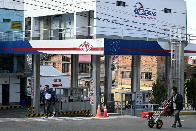 Men walk past an empty gas station during a transport workers strike over the quality of diesel in La Paz, on March 25, 2026. (Photo by AIZAR RALDES / AFP)