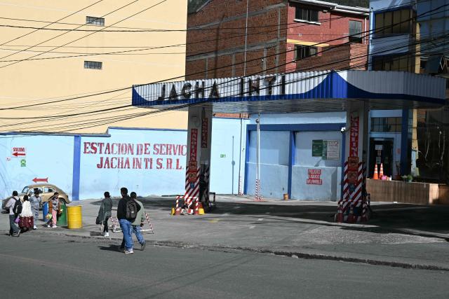 People walk past an empty gas station during a transport workers strike over the quality of diesel in La Paz, on March 25, 2026. (Photo by AIZAR RALDES / AFP)