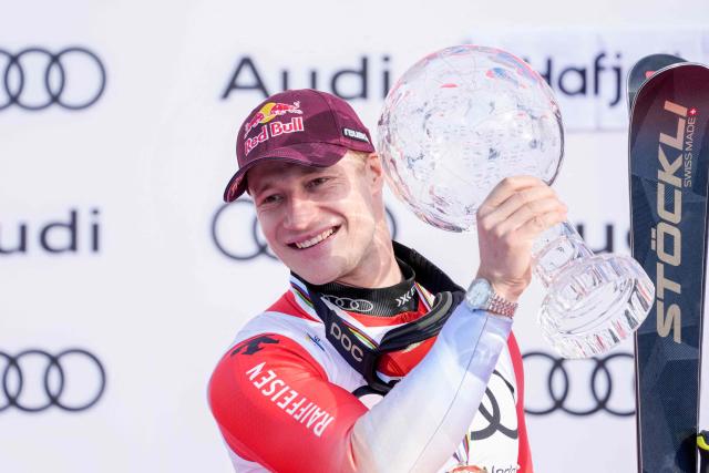 Austria's Marco Odermatt celebrates on the podium with the trophy as overall winner of the 2025/2026 Men's Alpine World Cup in Hafjell on March 25, 2026. (Photo by Cornelius Poppe / NTB / AFP) / Norway OUT