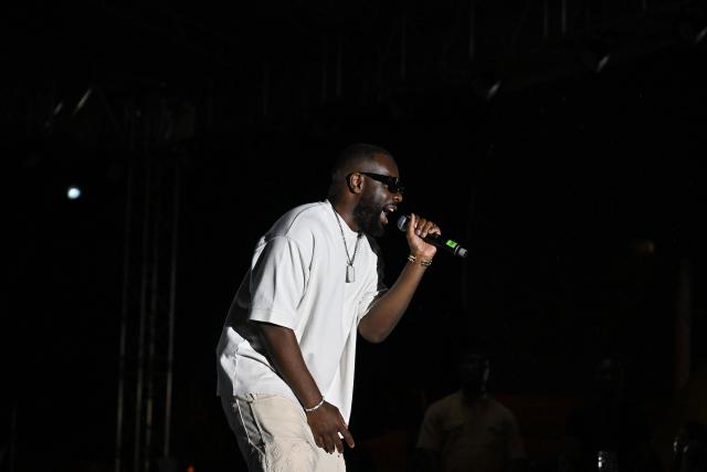 (FILES) Congolese-French rapper and singer GIMS performs during a concert of the Anoumabo Urban Music Festival (FEMUA) at the National Institute of Youth and Sports (INJS) in Abidjan in on May 17, 2024. Rapper Gims is in police custody in an organized money laundering case announced the organized crime prosecutor’s office on March 25, 2026. (Photo by Sia KAMBOU / AFP)