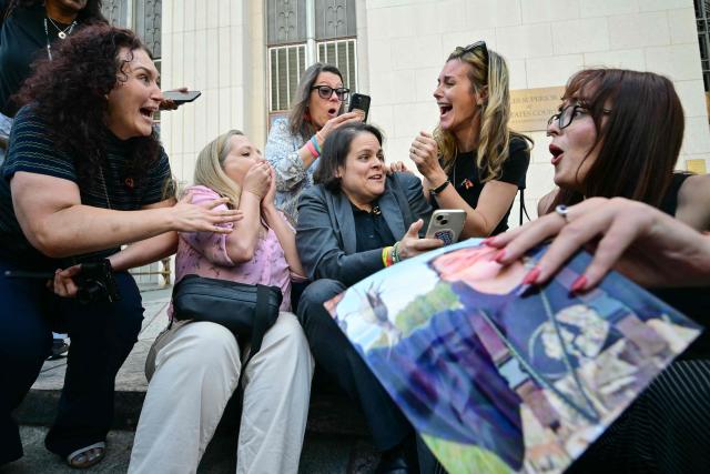 Laura Marquez-Garrett (C), plaintiffs' attorney for SMVLC (Social Media Victims Law Center), gathers with family members of victims as they react to news that the jury has found Meta and YouTube liable in the social media addiction trial, outside the Los Angeles Superior Court , in Los Angeles, on March 25, 2026. (Photo by Frederic J. Brown / AFP)