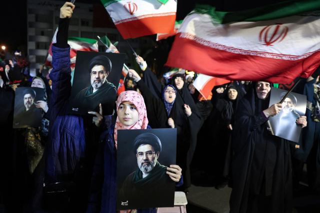 People wave national flags and hold portraits of Iran's supreme leader Mojtaba Khamenei as they march in support of the Iranian armed forces in central Tehran on March 25, 2026. President Donald Trump is ready to "unleash hell" if Iran doesn't accept a deal to end the Middle East war, the White House warned on March 25, adding that talks continued despite Tehran reportedly rejecting a proposed US peace plan. (Photo by AFP) / 