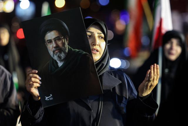 A woman holds a portrait of Iran's supreme leader Mojtaba Khamenei as people march in support of the Iranian armed forces in central Tehran on March 25, 2026. President Donald Trump is ready to "unleash hell" if Iran doesn't accept a deal to end the Middle East war, the White House warned on March 25, adding that talks continued despite Tehran reportedly rejecting a proposed US peace plan. (Photo by AFP) / 
