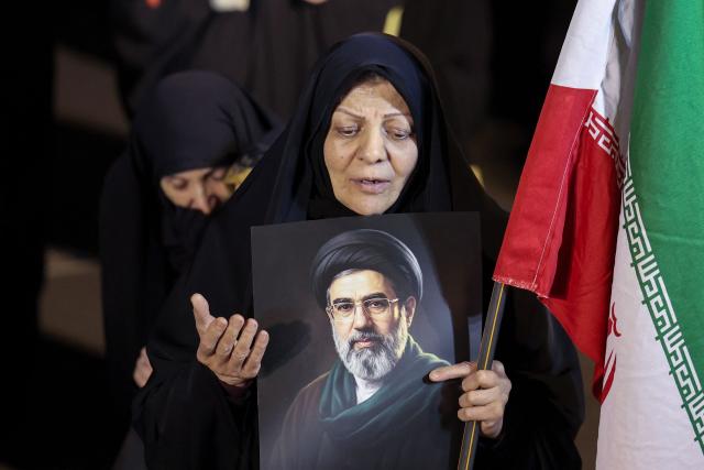TOPSHOT - A woman holds a portrait of Iran's supreme leader Mojtaba Khamenei as people march in support of the Iranian armed forces in central Tehran on March 25, 2026. President Donald Trump is ready to "unleash hell" if Iran doesn't accept a deal to end the Middle East war, the White House warned on March 25, adding that talks continued despite Tehran reportedly rejecting a proposed US peace plan. (Photo by AFP) / 