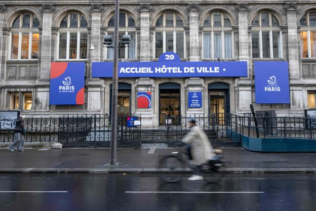A cyclist rides past the entrance of the tourist reception of the Hotel de Ville (Paris city hall) in Paris on March 25, 2026. (Photo by Blanca CRUZ / AFP)