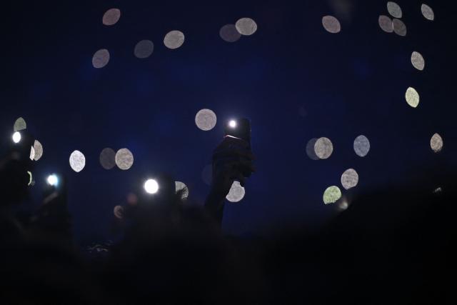 Fans hold smartphones with activated flashes during a concert in tribute to French late rapper Werenoi at the Accor Arena in Paris on March 25, 2026. (Photo by JULIEN DE ROSA / AFP)