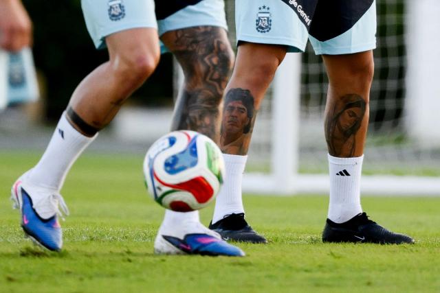 The tattooed legs of Argentina's midfielder Enzo Fernandez (L) and defender Gabriel Rojas (R) are pictured during a training session in Ezeiza, Buenos Aires province, Argentina on March 25, 2026. Argentina will play a friendly match against Mauritania on March 27 at the La Bombonera Stadium in Buenos Aires. (Photo by Luis ROBAYO / AFP)