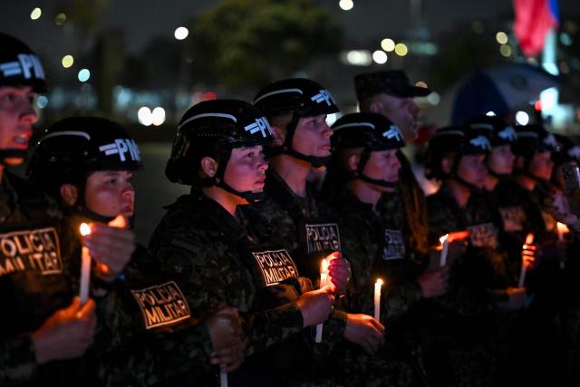 Colombian military police officers hold candles during vigil for the victims of the Colombian Air Force Hercules crash in Puerto Leguizamo, in Bogota on March 25, 2026. At least 69 soldiers and police officers were killed in one of the deadliest air accidents in Colombia's recent history, according to a new March 24 tally of the crash, which the government attributed to a ‘junk’ aircraft donated by the United States. (Photo by Daniel MUNOZ / AFP)