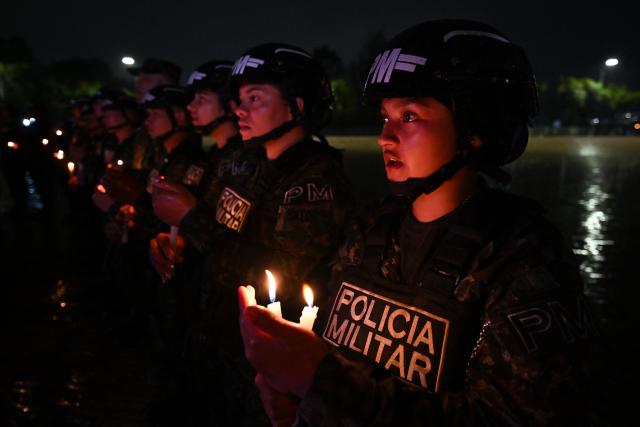 Colombian military police officers hold candles during vigil for the victims of the Colombian Air Force Hercules crash in Puerto Leguizamo, in Bogota on March 25, 2026. At least 69 soldiers and police officers were killed in one of the deadliest air accidents in Colombia's recent history, according to a new March 24 tally of the crash, which the government attributed to a ‘junk’ aircraft donated by the United States. (Photo by Daniel MUNOZ / AFP)