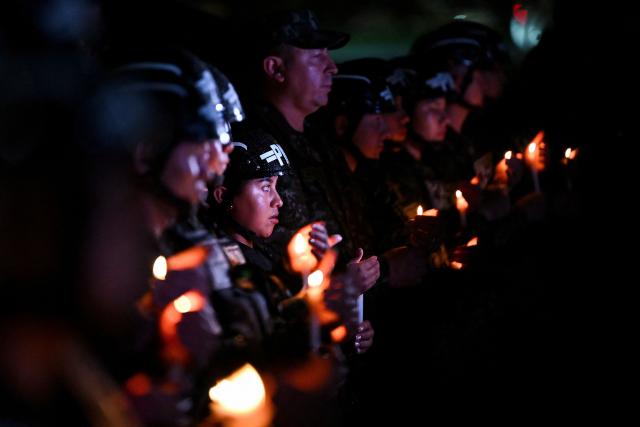 TOPSHOT - Colombian military police officers hold candles during a vigil for the victims of the Colombian Air Force Hercules crash in Puerto Leguizamo, in Bogota on March 25, 2026. At least 69 soldiers and police officers were killed in one of the deadliest air accidents in Colombia's recent history, according to a new March 24 tally of the crash, which the government attributed to a ‘junk’ aircraft donated by the United States. (Photo by Daniel MUNOZ / AFP)
