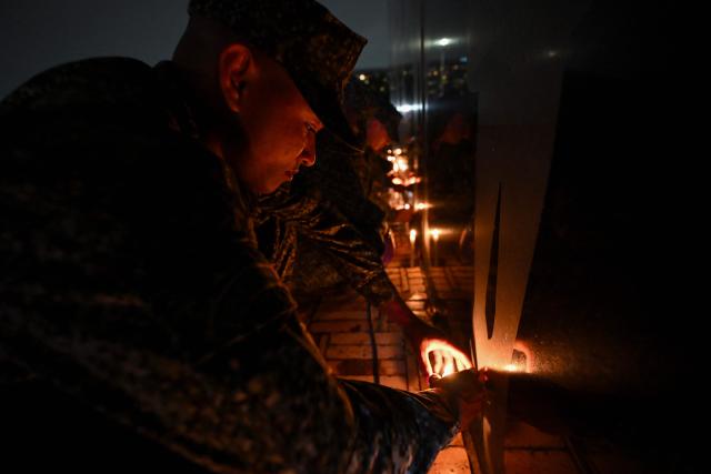 Colombian soldiers light candles at the Monument to the Fallen during a vigil for the victims of the Colombian Air Force Hercules crash in Puerto Leguizamo, in Bogota on March 25, 2026. At least 69 soldiers and police officers were killed in one of the deadliest air accidents in Colombia's recent history, according to a new March 24 tally of the crash, which the government attributed to a ‘junk’ aircraft donated by the United States. (Photo by Daniel MUNOZ / AFP)