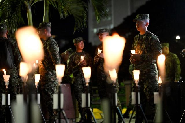 Colombian soldiers hold candles during a vigil for the victims of the Colombian Air Force Hercules crash in Puerto Leguizamo, in Cali, Colombia on March 25, 2026. At least 69 soldiers and police officers were killed in one of the deadliest air accidents in Colombia's recent history, according to a new March 24 tally of the crash, which the government attributed to a ‘junk’ aircraft donated by the United States. (Photo by Joaquнn SARMIENTO / AFP)