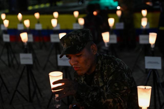 A Colombian soldier lights a candle during a vigil for the victims of the Colombian Air Force Hercules crash in Puerto Leguizamo, outside La Ermita church in Cali, Colombia on March 25, 2026. At least 69 soldiers and police officers were killed in one of the deadliest air accidents in Colombia's recent history, according to a new March 24 tally of the crash, which the government attributed to a ‘junk’ aircraft donated by the United States. (Photo by Joaquнn SARMIENTO / AFP)