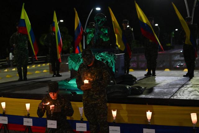 Colombian soldiers light candles during a vigil for the victims of the Colombian Air Force Hercules crash in Puerto Leguizamo, outside La Ermita church in Cali, Colombia on March 25, 2026. At least 69 soldiers and police officers were killed in one of the deadliest air accidents in Colombia's recent history, according to a new March 24 tally of the crash, which the government attributed to a ‘junk’ aircraft donated by the United States. (Photo by Joaquнn SARMIENTO / AFP)